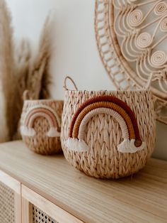 two woven baskets sitting on top of a wooden table next to a mirror and plant