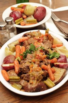 two plates filled with meat and vegetables on top of a table next to utensils