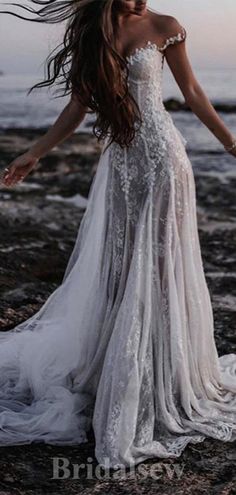 a woman standing on top of a beach next to the ocean wearing a white dress