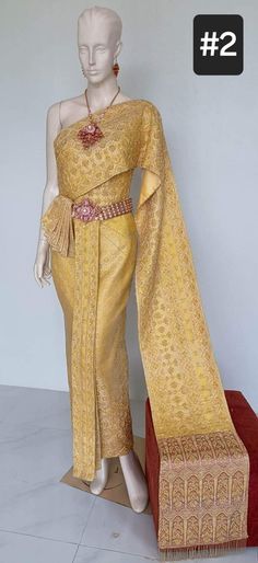 a mannequin is dressed in a yellow and gold dress with an elaborate shawl