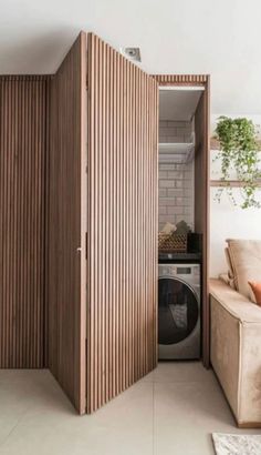 an open closet in the corner of a living room with a washer and dryer