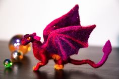 a purple dragon figurine sitting on top of a table next to two shiny balls