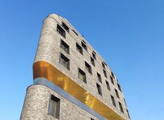 a tall brick building with windows and gold trim on it's side against a blue sky