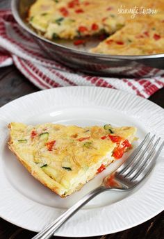 a slice of quiche on a white plate with a fork next to the pie