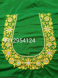 an embroidered green cloth with yellow flowers and leaves on it, in front of a wooden floor