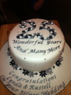 a white cake with black and silver decorations on the top that says 25 wonderful years