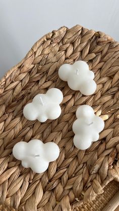 three white candles sitting on top of a wicker basket