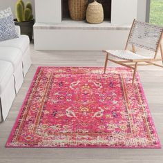 a living room with a white couch and pink rug on the floor next to a fire place