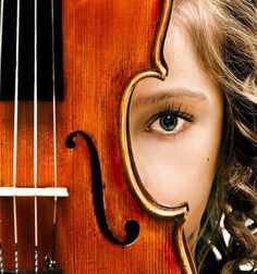 a close up of a violin with a person's face reflected in the mirror