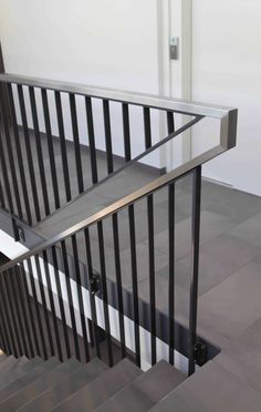 a metal hand rail on the bottom of a stair case in a room with white walls