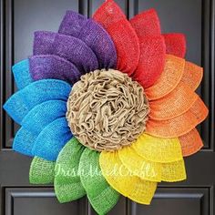 a multicolored sunflower wreath is hanging on the front door with burlocks