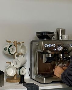 a man is working on an espresso machine with coffee cups next to him