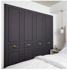 a bedroom with black cabinets and white sheets