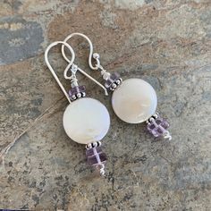 The pearls used in these earrings are stunning! They are grade AAA pearl disks. Beautiful, natural luster. Square lavender amethyst heishi sit above and below the pearl. Accent beads, headpins and ear wires are all sterling silver. 1.75 inches long from the top of the ear wire to the bottom of the earring. Pearl disk size: 15mm / 3mm thick Your jewelry will arrive in a cotton lined kraft box within a padded postal envelope. I use USPS first class mail. This usually takes 3 to 5 days to ship. Int Purple Natural Stones Round Earrings, Round Purple Earrings With Natural Stones, Purple Earrings With Natural Stones, Purple Round Pearl Earrings For Gift, Earring Pearl, Lavender Amethyst, Labradorite Bracelet, Coin Earrings, Coin Pearls