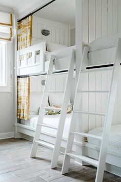 two white bunk beds sitting next to each other on top of a hard wood floor