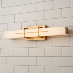 a bathroom light that is on the side of a brick wall with white bricks behind it