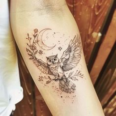 an owl tattoo on the arm with stars and moon in it's wings is shown