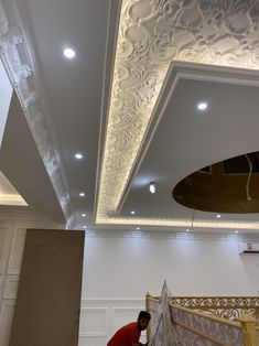 a man working on a ceiling in a room with white walls and lights above it