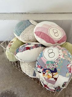 a basket filled with lots of pillows on top of a cement floor next to a wall