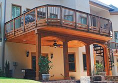 a large house with a wooden deck and stairs leading up to the upper level balcony