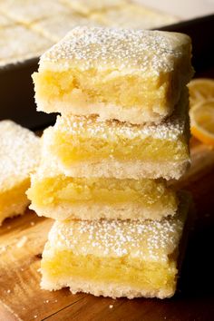 four lemon bars stacked on top of each other with sugar sprinkled on them