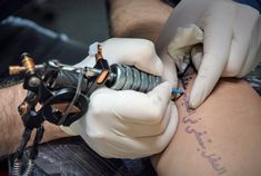 a tattoo artist working on someone's arm with scissors and wires attached to it