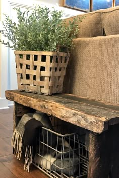 a couch with a basket on top of it next to a planter filled with plants