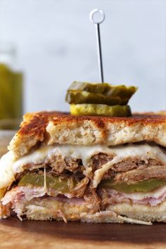 a cut in half sandwich sitting on top of a cutting board next to pickles