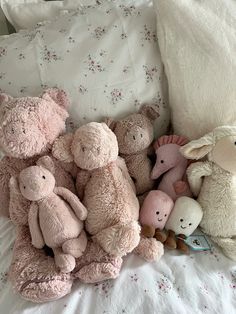 a pile of stuffed animals sitting on top of a bed next to pillows and blankets