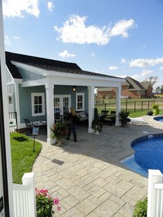 a woman walking into a backyard with a pool and gazebo in the foreground