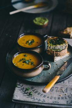 two bowls of soup on a plate with bread