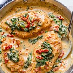 chicken with spinach and tomato sauce in a silver skillet on a white table