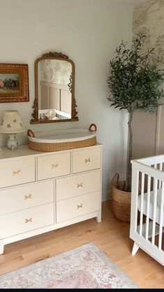 a baby crib and dresser in a room with a mirror on the wall above it