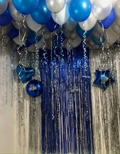 balloons and streamers are hanging from the ceiling in front of a curtain that is draped with silver sequins