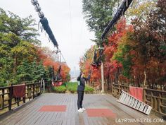 a person on a wooden bridge holding onto some kind of device with trees in the background