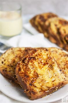 two pieces of grilled cheese sit on a plate next to a glass of milk