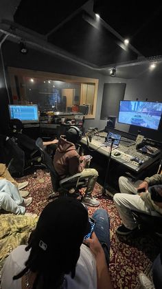 a group of people sitting in front of computer monitors on top of a floor next to each other