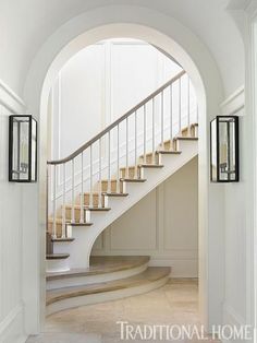 an arched doorway leading to a staircase with white walls and beige carpet on the floor