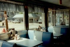 the inside of a restaurant with tables and chairs in front of large windows looking outside