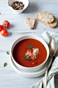 a bowl of tomato soup with bread on the side