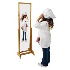 a woman standing in front of a mirror looking at her reflection wearing a white hat