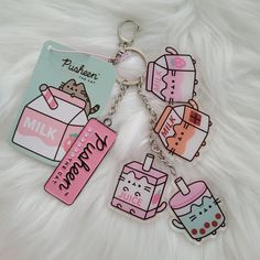 hello kitty keychains with milk, milk carton and cat on them sitting on a fluffy white surface