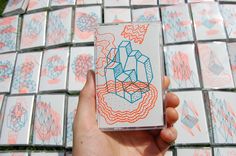 a person holding up a small box with designs on it in front of some tiles