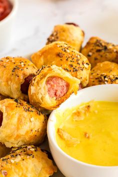 hotdogs wrapped in bread and dipping sauce on a plate with other food items