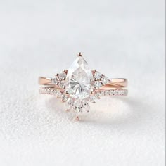 an engagement ring with a pear shaped diamond surrounded by smaller diamonds