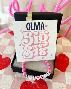 a pink beaded bracelet sitting on top of a table next to a sign that says big sister