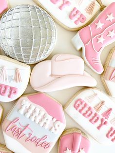 decorated cookies with pink and white frosting are arranged on a table next to a silver ball