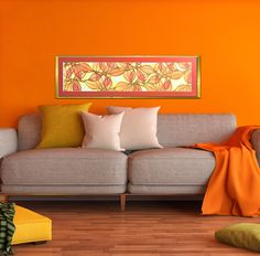 a living room with orange walls and white pillows on the couches, while a painting hangs above it