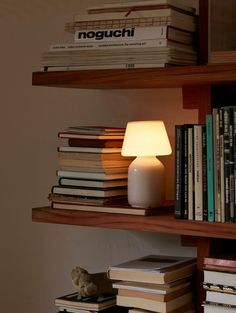 a book shelf filled with books next to a lamp