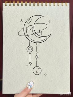 someone is holding up a drawing on paper with the moon and stars hanging from it